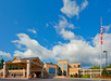 Hotel exterior with a large entrance, American flag on a pole, and a clear blue sky with clouds in the background.