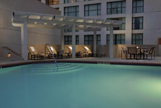 Outdoor pool with patio chairs and sun loungers.