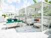 An outdoor lounge area with covered couches on the left and green chairs sitting in the sun on right at Holiday Inn & Suites.