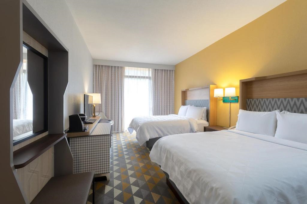 Two queen beds, flat-screen TV, a coffee maker, and a work desk with a lamp.