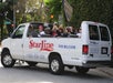 A tour van labeled "StarLine" carries passengers with cameras on a tree-lined street near a Beverly Hills sign.