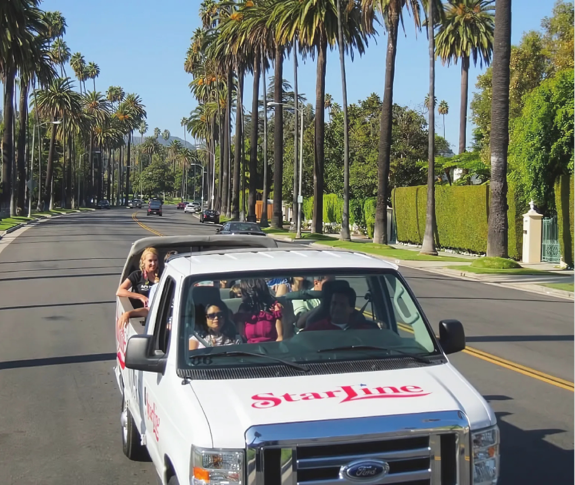 A white StarLine tour van with passengers drives down a palm tree-lined street in a sunny neighborhood.