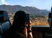 Person in a car takes a photo of a hilly landscape with a distant sign on a mountain.