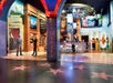 Entrance to a wax museum with large Hollywood-themed displays, staff at a reception desk, and star tiles on the floor resembling the Walk of Fame.