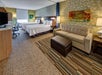 Two queen beds, sofa bed/seating area, desk and chair inside a guest room.