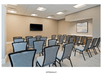 A conference room with rows of gray chairs lined up in front of a TV on the fall wall at the Homewood Suites By Hilton Panama City Beach.