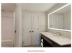 A modern bathroom with a shower and tub combo on the left, a vanity with a large lit mirror on the right, and a door on the far wall.