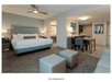 A spacious hotel room furnished with a king-size bed, sofa with ottomans, dining table and a kitchenette.