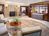Hotel lobby with a fireplace, front desk, seating area with a round wooden table, and a plant on the table.
