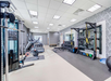 Modern gym with treadmills, stationary bikes, weight racks, resistance machines, exercise balls, and other fitness equipment in a well-lit room with patterned walls.
