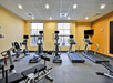 A fitness facility with yellow walls and a row of different cardio equipment and a weight machine at the Homewood Suites by Hilton New Braunfels.