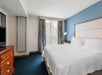 One king bed, bedside lamp, and TV in a guest room.