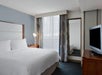 One king bed, bedside lamp, and TV in a guest room.