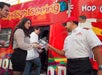 People boarding a red sightseeing tour bus, with a staff member handing out brochures.