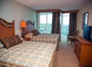 Guest room with two beds with floor-to-ceiling windows and a balcony with a view.