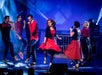 Men and women in red and black dancing and singing on stage at Hot Rods & High Heels in Branson, Missouri.