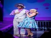 A man and woman wearing pastels smiling on stage at Hot Rods & High Heels in Branson, Missouri.