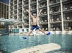 A child enjoying in the outdoor pool with a swim up bar and plenty of lounge chairs.