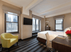 One King bed, flat-screen TV, work area, and a comfortable soft seating inside a guest room.