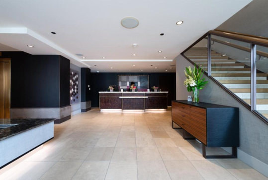 A spacious lobby and front desk located beside the main stairs.