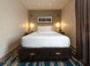 One king bed, telephone and wall-mounted bedside lamps inside a guest room.