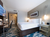 One king bed, lamps, flat-screen TV, and work desk with chair inside a non-smoking room.