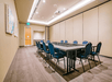 A meeting room with a gray table surrounded by blue chairs with art on the wall to the left at the Hotel Indigo Denver Downtown.