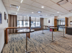 Empty conference room with round tables, wood accents, striped carpet, and large window with curtains.
