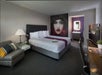 Guest room with one king bed, soft seating, flat-screen TV, and work desk.