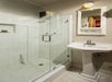 Private bathroom with sink, small mirror, and glass enclosed shower.