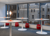 A modern conference room with large windows showing the city and several white round standing tables with tea lights in the middle.