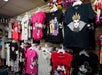 T-shirts featuring Disney characters and villains, including Mickey Mouse and the Evil Queen, are displayed on hangers and racks in a retail store.