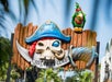A colorful sign reading "Castaway Cove" features a skull with a pirate hat and sword, and a green parrot perched on top, against a backdrop of trees and blue sky.