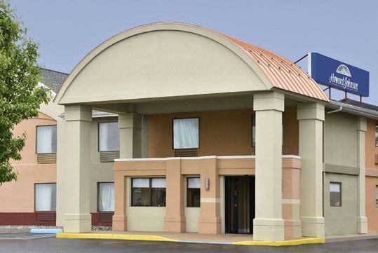 A tan and beige hotel building with large columns, an arched roof, and a Howard Johnson sign on top.