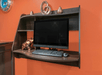A small business center station with a computer on a shelf and some knick knacks around it on a bright orange wall.