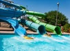 The Bonzai Pipeline featuring three slides from a four-story tower with two people in tubes splashing into the water.