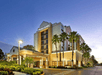 Front exterior of the Hyatt Place Orlando with palm trees lining the sides and the walkways with the sun setting in the background.
