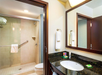 Hotel bathroom with a walk-in shower, granite countertop sink, towels, and toiletries.