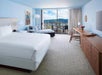 On bed, seating area, and private balcony inside a guest room with view.