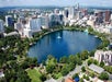Aerial view of a city skyline with a large, circular lake surrounded by greenery and buildings.