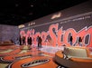 People stand and walk inside an immersive exhibit featuring large Rolling Stone magazine graphics projected on the walls and floor.