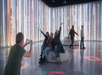 People pose for a photo in a room with tall, colorful light displays and circular seating.