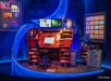 An animator’s desk with a digital drawing tablet, dual monitors, sketchbooks, art supplies, and animation artwork displayed on blue-lit walls.