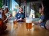 The tour guide wearing crawling tours shirt and the tourists with beers on the table at Boston Crawling tours   