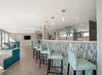 Spacious bar area with teal chairs, a tiled counter, and multiple taps. Modern lighting and seating areas are visible in the background.