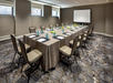 Meeting facility with a long table, chairs and a white screen projector.