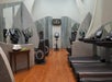 A gym room with treadmills, stationary bikes, and mirrors. A table with towels and apples is on the side.