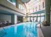 Indoor swimming pool with lounge chairs, skylight, and plants in a modern facility.