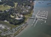Aerial view of a marina with multiple docks and boats, adjacent to a waterfront residential area surrounded by trees and greenery.
