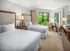 Two beds, seating area, and balcony inside a guest room.